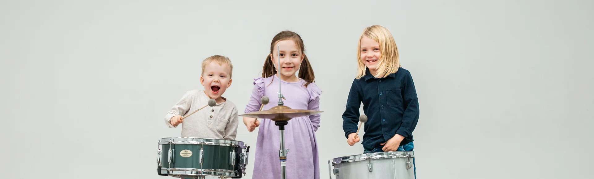 Iloiset lapset soittavat lyömäsoittimia