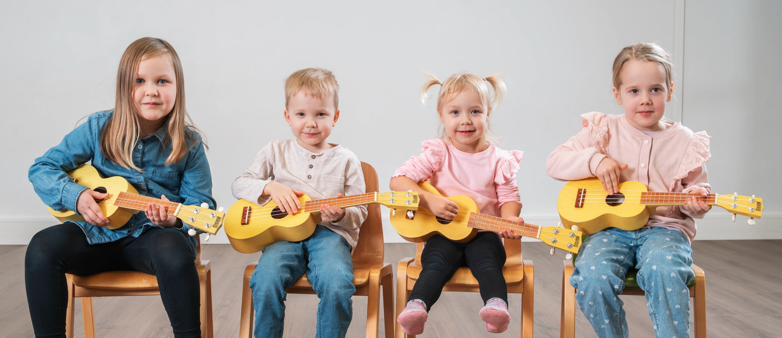 Pieniä lapsia keltaiset ukulelet sylissä